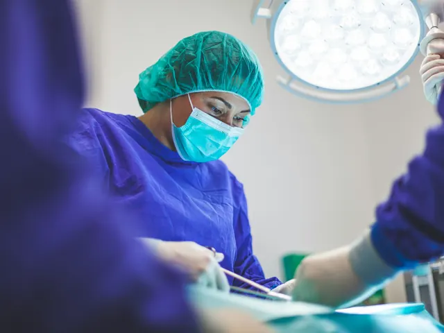 Cirurgiã de touca e máscara durante uma cirurgia